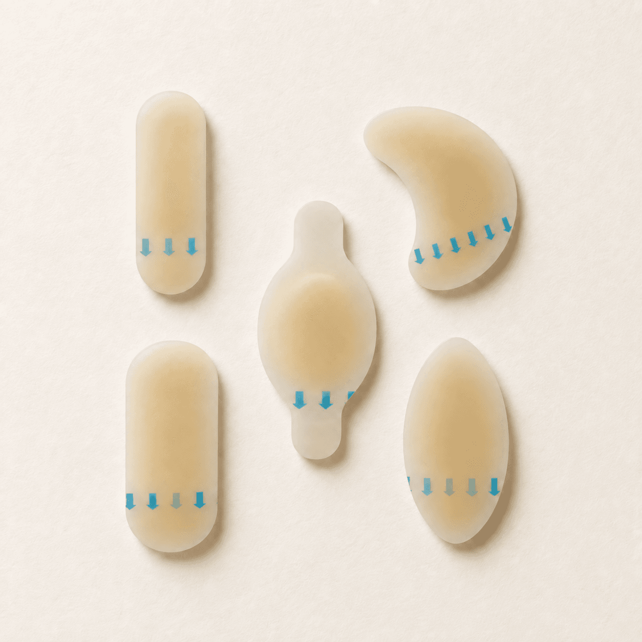 All five MEND hydrocolloid blister patch shapes — tabbed oval, large capsule, almond, small capsule and kidney — laid flat on a cream background